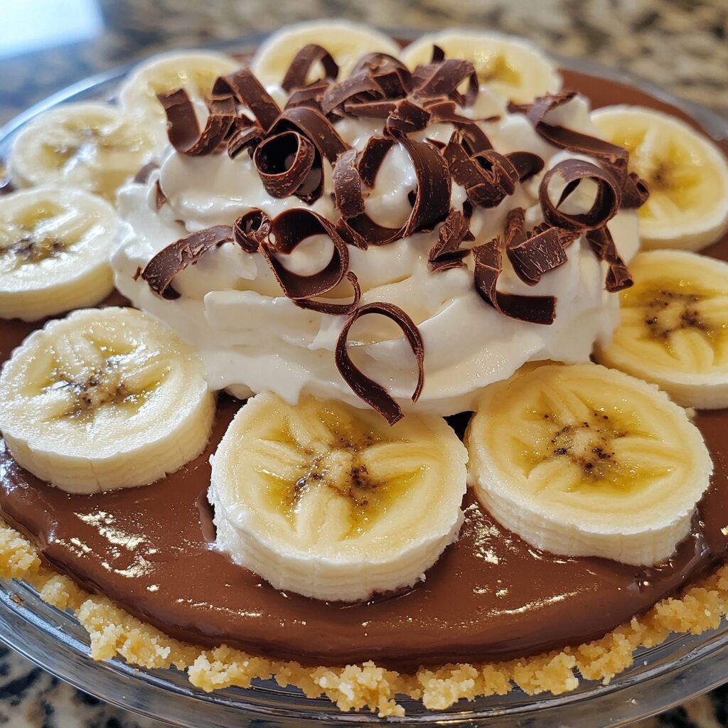 Chocolate 5-Layer Chocolate Banana Pudding Pie showing layered pudding, bananas, chocolate crust, and whipped topping